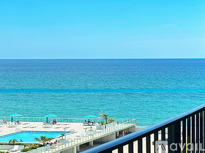 A beautiful beach scene with a pool and people relaxing.
