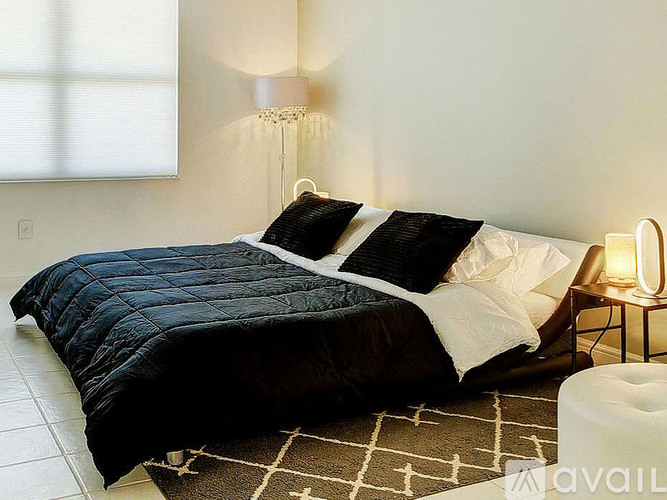 A black and white bedroom with a large bed and a lamp.