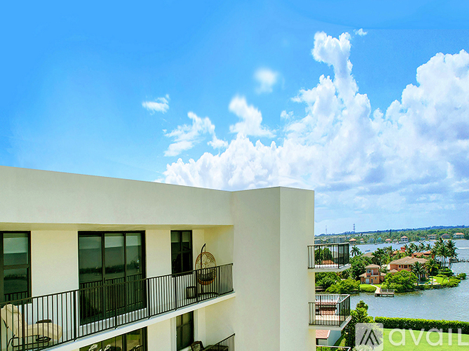 A white building with balconies overlooks a body of water.