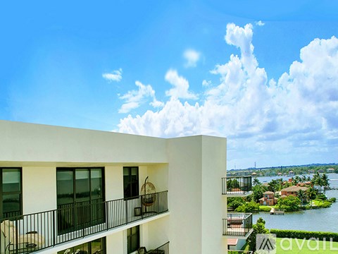 A white building with balconies overlooks a body of water.
