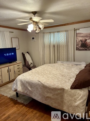 A bedroom with a bed, a ceiling fan, and a digital clock showing 4:10 PM.