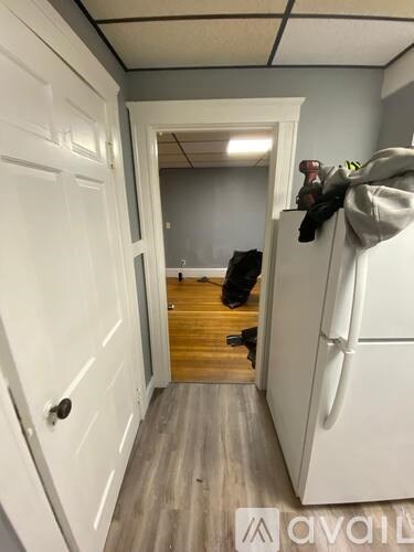 A hallway with a white door and a white fridge with a grey towel hanging on it.