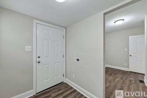 A white door is in a room with a mirror on the wall.