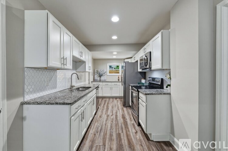 A kitchen with white cabinets and a wooden floor.
