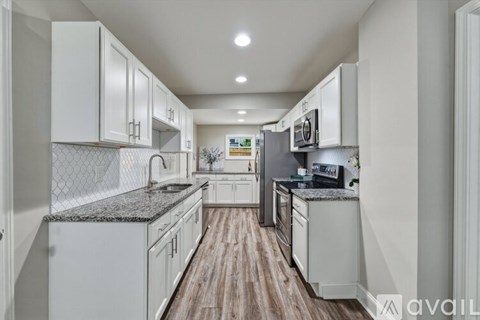 A kitchen with white cabinets and a wooden floor.