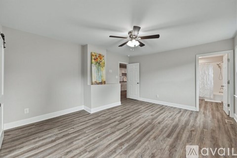 A spacious room with a ceiling fan and wood flooring.