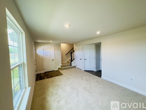 A spacious room with a staircase leading to another floor.