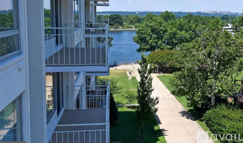 A modern apartment building with a balcony overlooking a river and greenery.