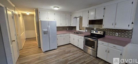 A kitchen with white cabinets and a wooden floor.