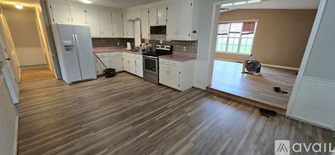 A kitchen with white cabinets and a wooden floor.