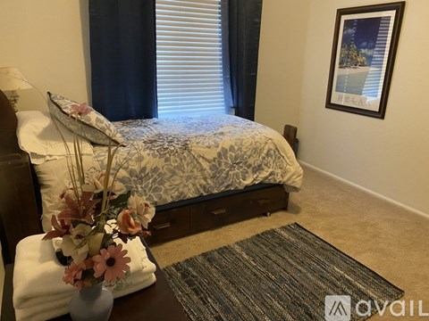 A bedroom with a bed, a vase with flowers, and a picture on the wall.