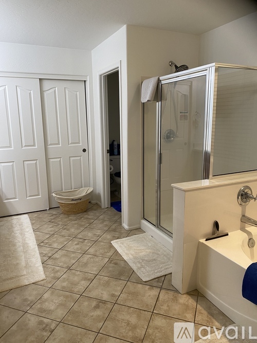 A bathroom with a white door, a white toilet, a white sink, and a white bathtub.