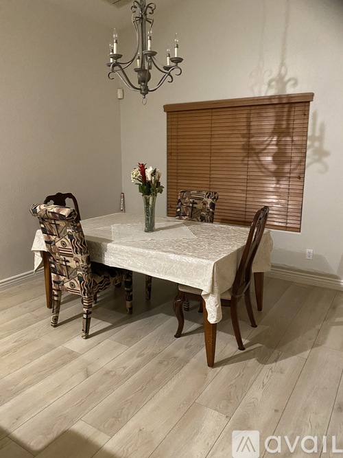 A dining room with a table set for two and a chandelier.