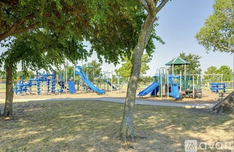 A playground with a blue slide and a green roofed structure.