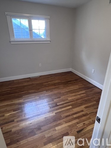 A room with wooden flooring and a window.