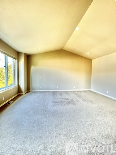 A spacious room with a carpeted floor and a large window.