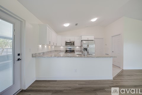 A kitchen with white cabinets and a marble countertop.