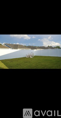 A white fence with a green lawn in front of a building.