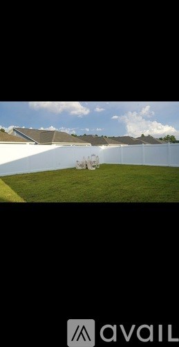 A white fence with a green lawn in front of a building.