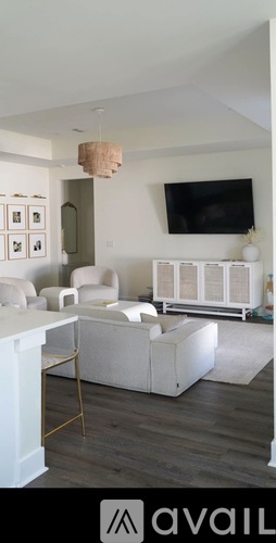 A living room with a white couch and a television mounted on the wall.