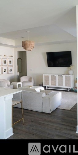A living room with a white couch and a television mounted on the wall.