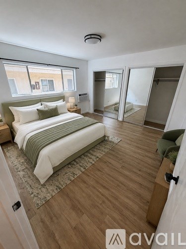 A bedroom with a bed, a window, and a wooden floor.