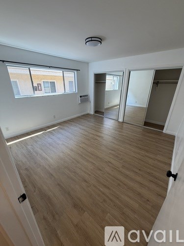 A room with wooden flooring and a window overlooking a building.