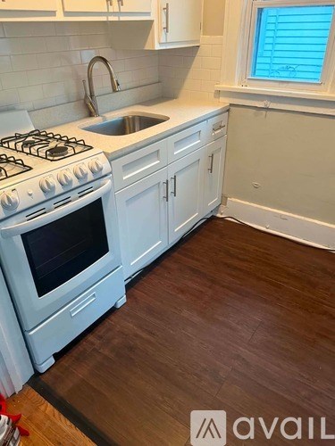 A kitchen with a white stove top oven and a white sink.