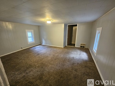 A room with carpeted floor and a door in the middle.