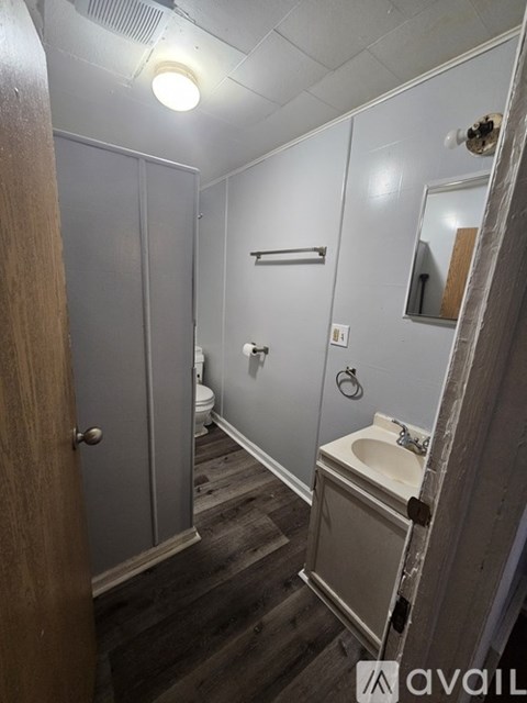 A bathroom with a toilet, sink, and mirror.