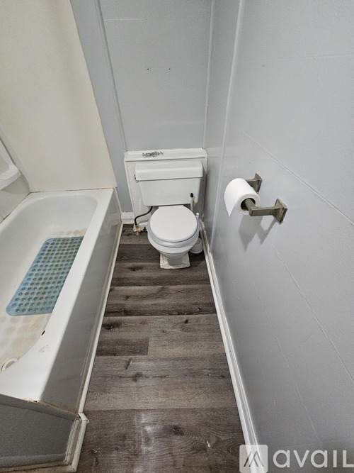 A white toilet sits in a bathroom next to a bathtub.