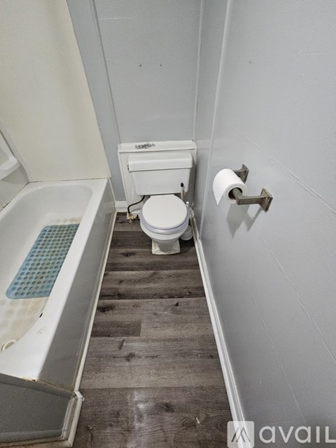 A white toilet sits in a bathroom next to a bathtub.