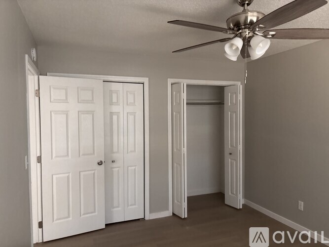 A room with a ceiling fan and two doors.