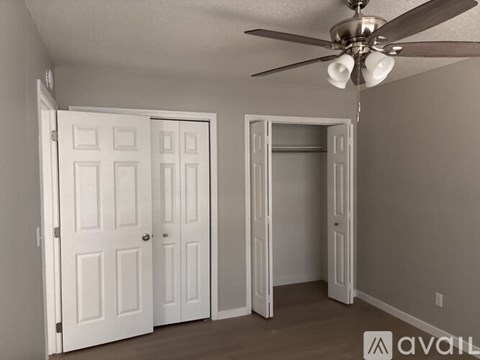 A room with a ceiling fan and two doors.