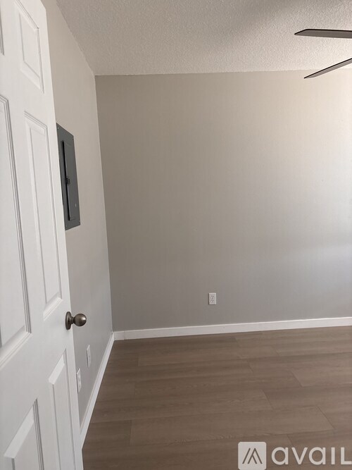A room with a white door and wooden flooring.