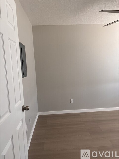 A room with a white door and wooden flooring.