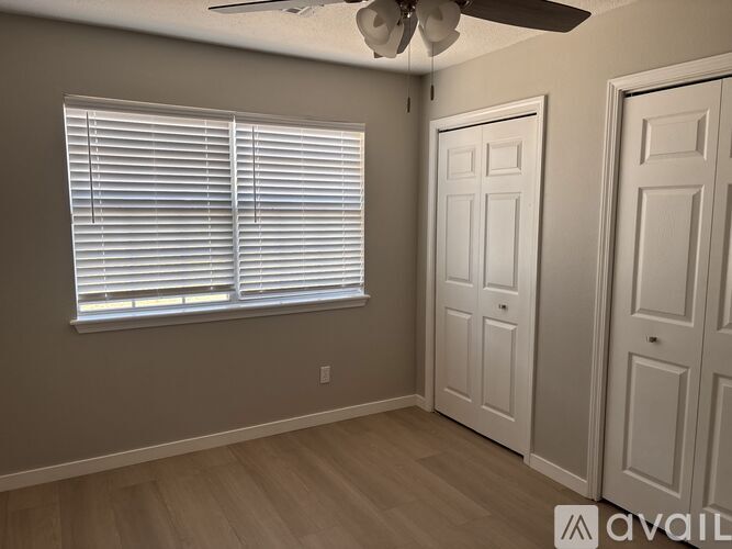 A room with a window covered by white blinds and a ceiling fan.