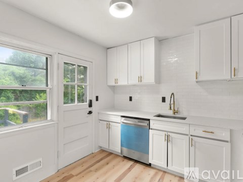 A kitchen with white cabinets and a window overlooking a green area.