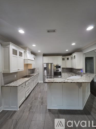 A modern kitchen with white cabinets and a marble countertop.