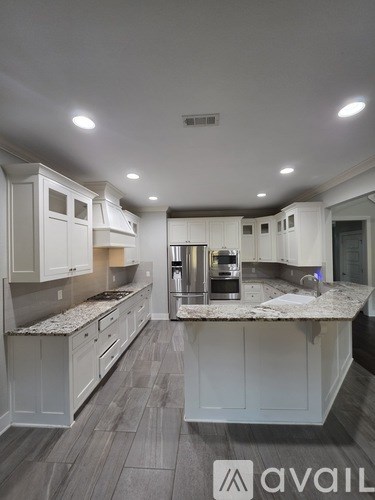 A modern kitchen with white cabinets and a marble countertop.