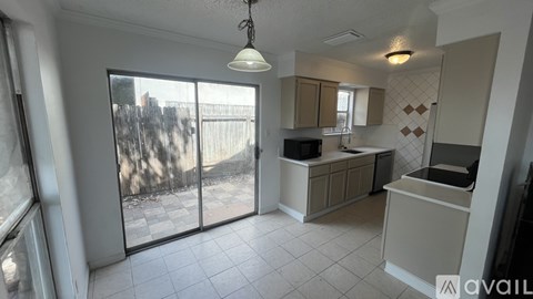 A kitchen with a sliding glass door leading to a backyard.