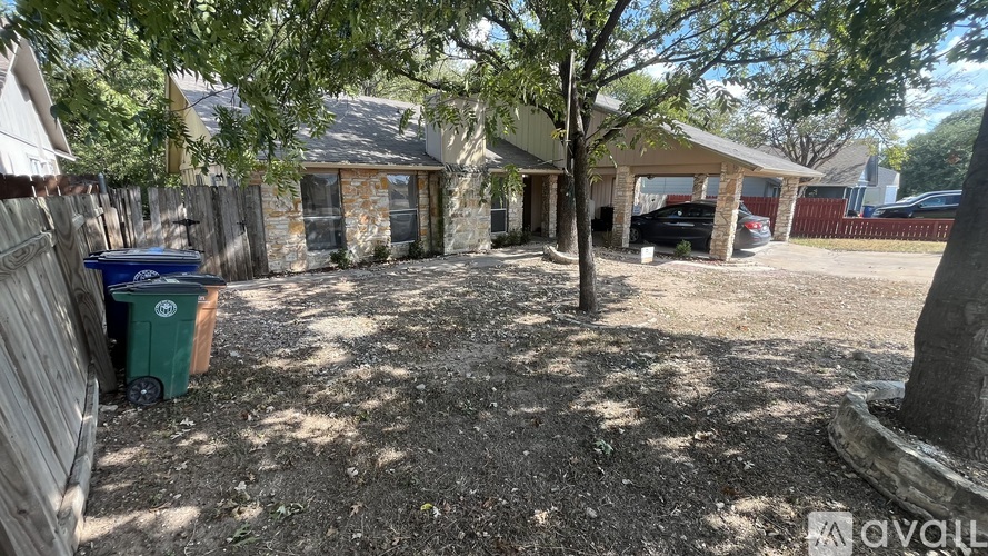 A backyard with a tree, a trash can, and a shed.