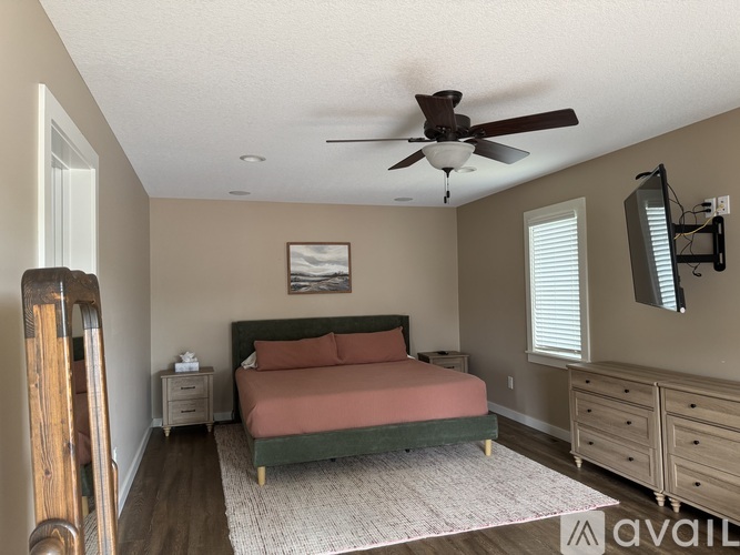A bedroom with a bed, dresser, and mirror.