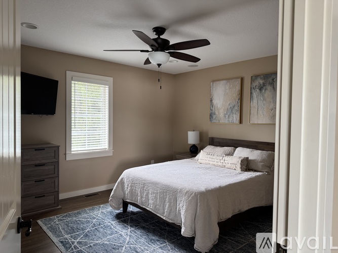 A bedroom with a bed, a ceiling fan, and a window with blinds.