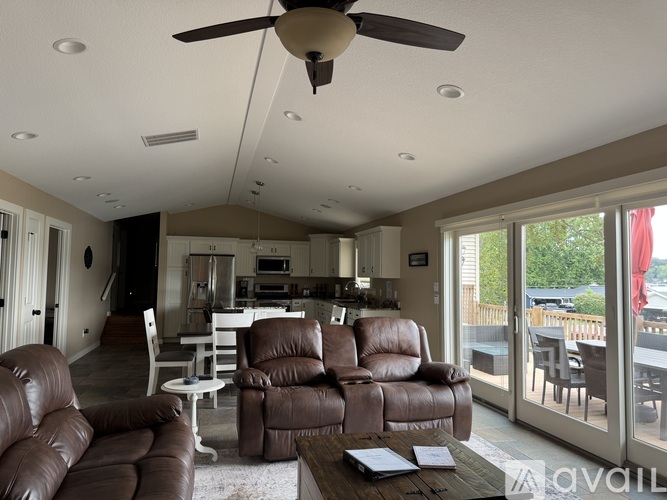 A living room with brown leather furniture and a ceiling fan.