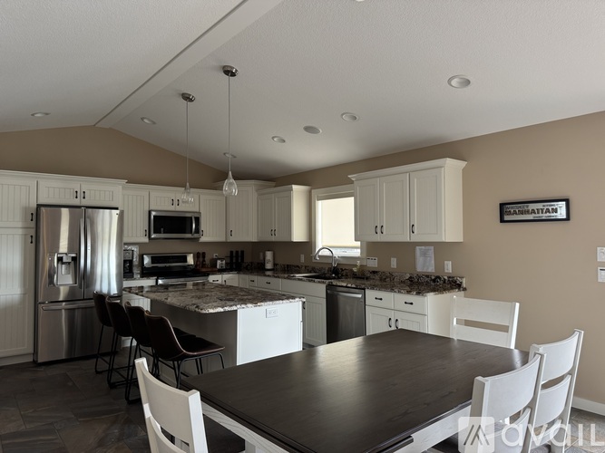 A kitchen with a table and chairs in front of it.