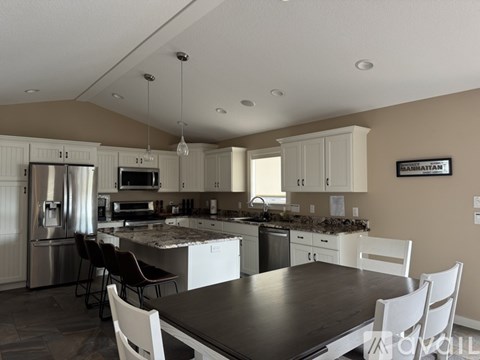 A kitchen with a table and chairs in front of it.