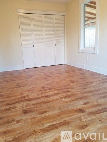 A room with wooden flooring and white closet doors.