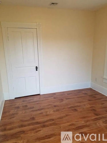 A room with a white door and wooden flooring.