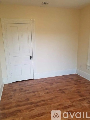 A room with a white door and wooden flooring.
